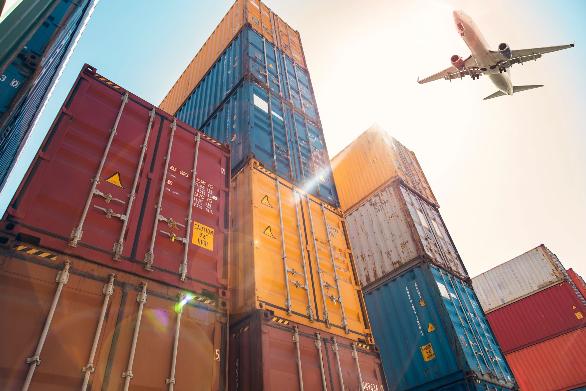 Airplane flying above cargo container.